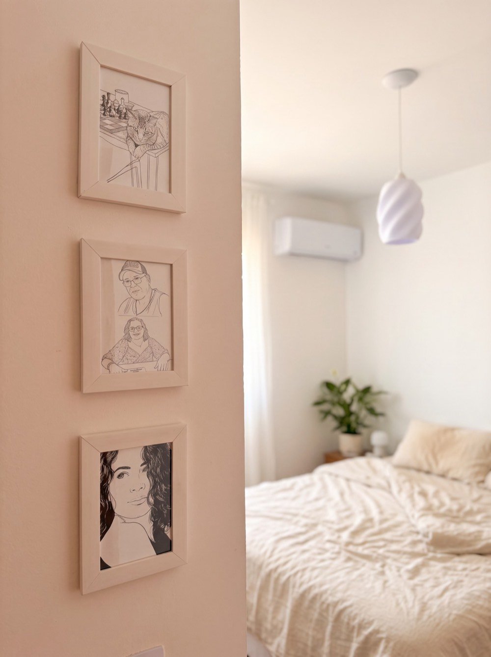 Três quadros em arte de linha com moldura branca pendurados na parede de um quarto
